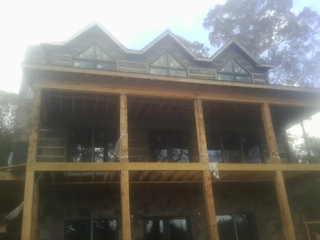 Dormers and porch framing on a large log home under construction — Roof Coating work by our crew in Three Forks