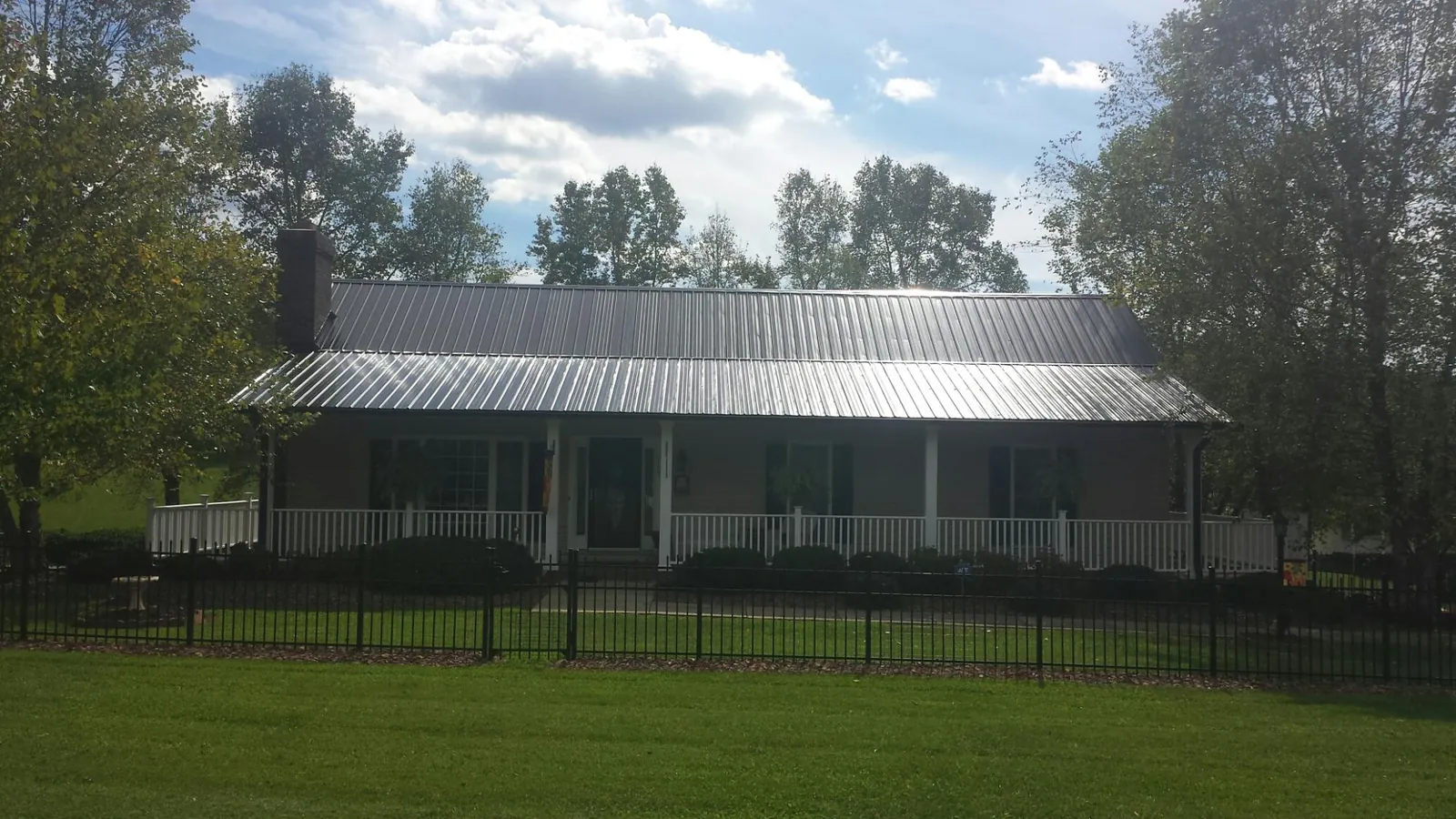 Gray metal roof on a brick ranch with a full width front porch — Gutter Guard Installation work by our crew in Three Forks
