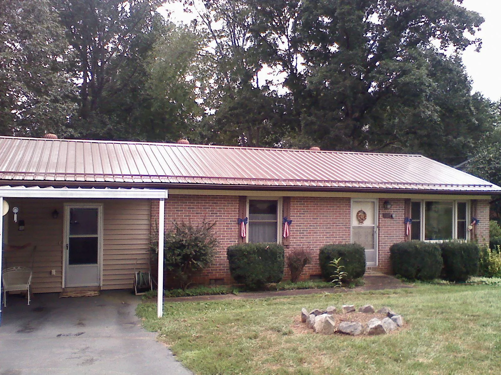 Bronze metal roof and carport on a brick ranch home — Roof Repair work by our crew in Three Forks